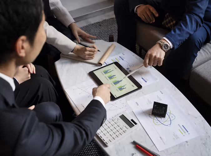 A group of people sitting around a table with a tablet.